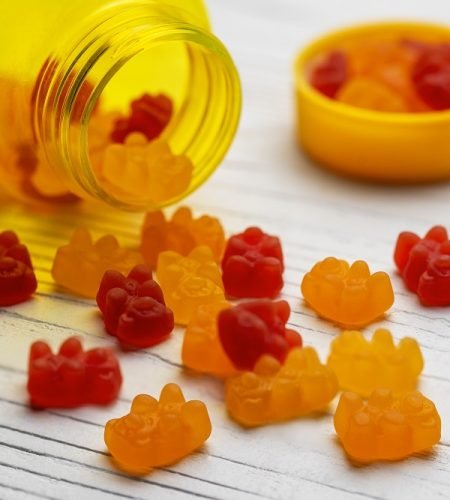 Vitamins for children,   jelly gummy bears candy on white wooden background